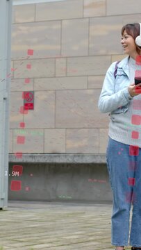 Vertical video: Mid-adult woman by stone wall tapping phone causing AR viewing social media metrics
