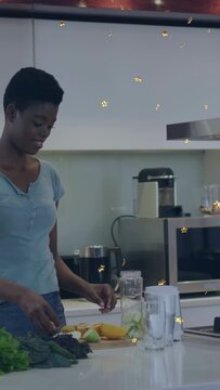 Vertical video: Cook picking up fruit on wood board filling jar for blender gold stars cross hands