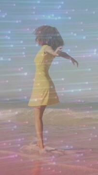 Vertical video: Woman starting dance as camera filming, twirling in surf, light overlay for travel