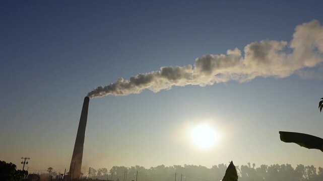 Black smoke is emitted from brick kilns in the early morning light, causing air pollution. Brick kilns emit polluting fumes or hazardous gases like CO2, CO, NOX, NO and SO2.