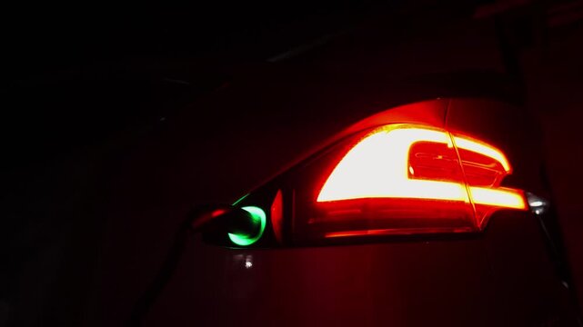 Electric car charging at evening. Power connector inserted into EV automobile. Process of recharging of e-vehicle battery. Environmentally friendly zero emission auto. Clean energy filling technology
