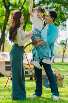 A family of three from Asia enjoyed using their laptops in the park and also enjoyed a picnic together in the park.
