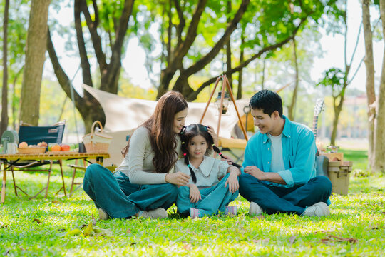 A family of three from Asia enjoyed using their laptops in the park and also enjoyed a picnic together in the park.