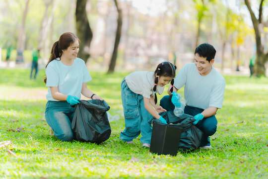 Environmental conservation concept: A cute little girl and her parents are picking up trash in the park. A family of volunteers is collecting trash in the forest. Environmental conservation concept.