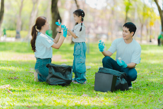 Environmental conservation concept: A cute little girl and her parents are picking up trash in the park. A family of volunteers is collecting trash in the forest. Environmental conservation concept.