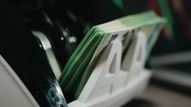 Automatic currency counter processing stack of euro banknotes continuously in modern financial setting. Concept business cash flow and financial system efficiency.
