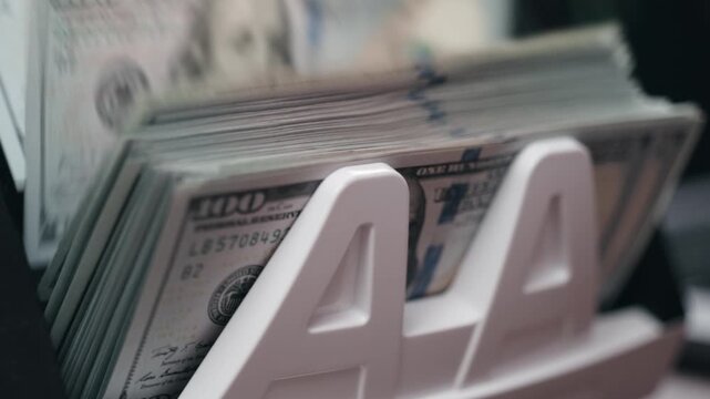 Money counter machine counting stack of US 100 dollar bills with high accuracy. Concept banking precision and cash control.

