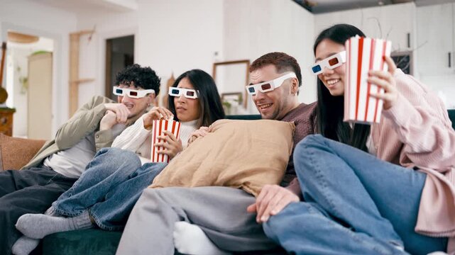 Frightened friends wearing 3D glasses and eating popcorn while watching a horror movie on the couch. Young people enjoying a film together