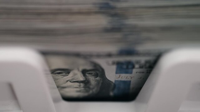 Currency counter machine counting stack of hundred dollar banknotes rapidly. Concept profit calculation and business finance.
