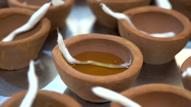 Macro view of a cotton wick placed inside a traditional clay diya being filled with oil highlighting preparation for Diwali lighting and Indian festive rituals.