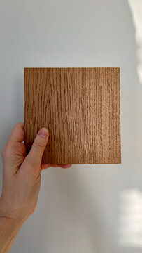 hand holding a wood material interior design honey oak sample in natural light