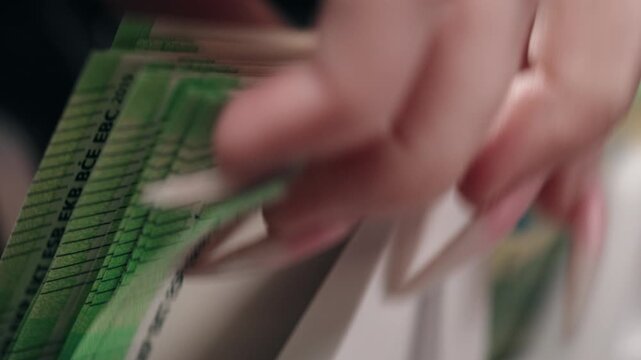 Close-up sequence of euro banknotes being organized in a white money holder, showcasing the detailed texture and design of the currency in a financial setting