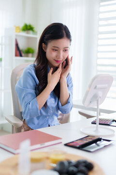 young Asian women applying makeup beauty routine skincare cosmetic mirror natural light white desk modern home office lifestyle wellness selfcare morning