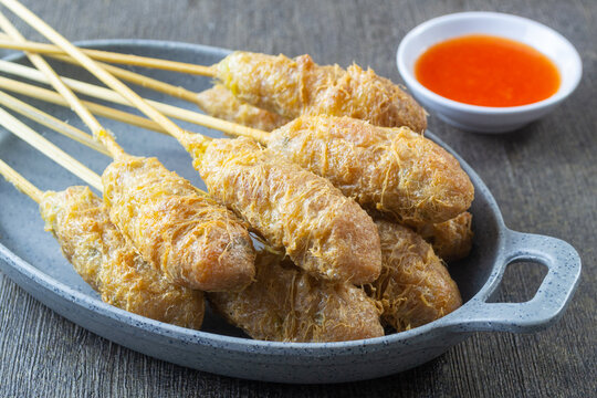 Indonesian street food sempol ayam served on a grey plate with spicy chili dipping sauce, deep fried chicken skewers coated with egg