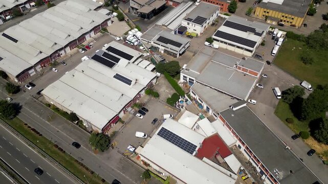 Industrial Park Aerial View: An aerial perspective reveals a sprawling industrial park featuring numerous warehouses and commercial buildings, interspersed with solar panels.