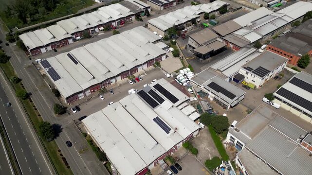 Aerial View of Industrial Park: An aerial perspective showcases a sprawling industrial park with rows of warehouses, solar panels on rooftops, and a nearby highway.