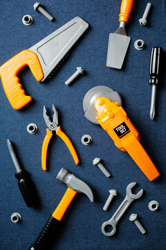 Vertical flat lay of colorful toy construction tools on blue jeans background