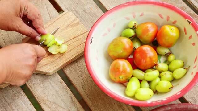 Slicing fresh bilimbi and tomatoes for indonesian cuisine