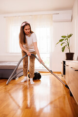 Fototapeta premium Woman vacuum cleaning floors while deep cleaning the house