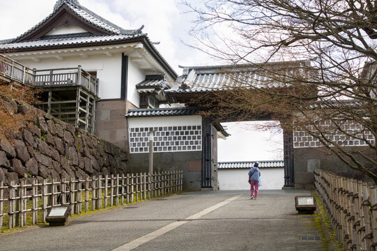 Woman walking on path toward Kahoku-mon Gate at Kanazawa Castle in Kanazawa, Japan