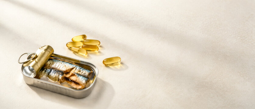 Canned sardines and omega capsules on neutral background