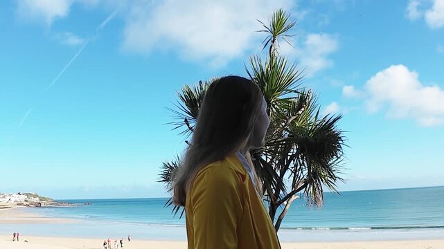 A woman walks on the evening seaside wearing yellow jacket