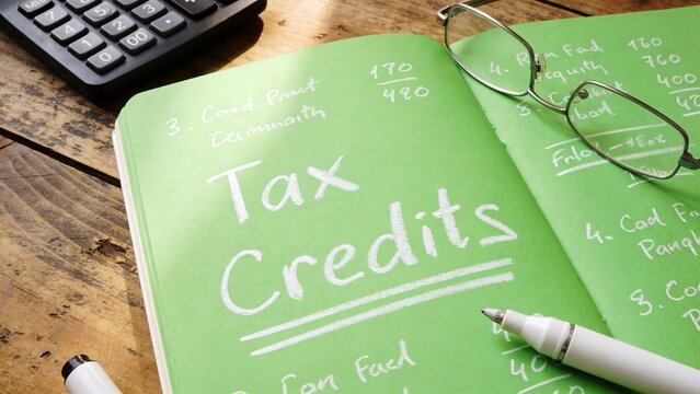 green notebook open Tax Credits handwritten calculator glasses marker finance planning
