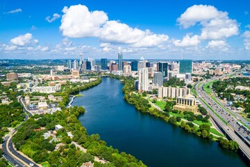 Fototapeta premium Austin Skyline in Summer Light: The Colorado River Winds Through a Lush Green Cityscape Beneath Bright Skies and Towering Modern Architecture.