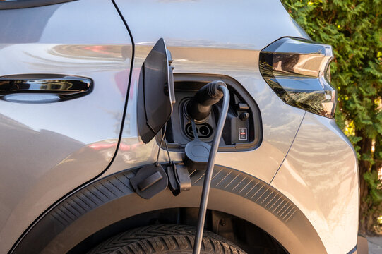 Electric car charging at home outdoors Electric vehicle plugged into a charger outside a building. Concept of home charging, renewable energy and modern lifestyle.