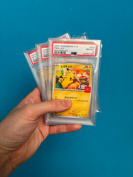 Hamburg, Germany - 04042026: male hand holding several PSA graded 2025 Japanese Pok&eacute;mon McDonald&rsquo;s promo Burger Pikachu cards.