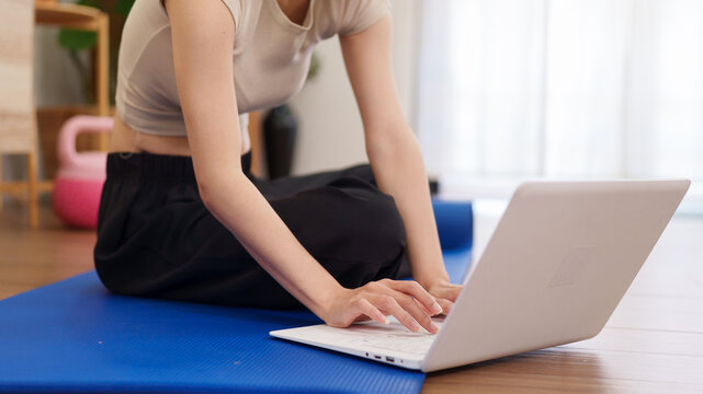 Asian women fitness instructor using laptop computer online training virtual class yoga workout exercise home gym workout mat wellness lifestyle healthy living