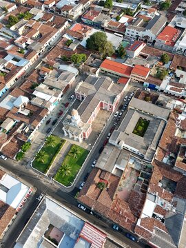 Church shaped like a cross. Aerial footage of Parroquia Nuestra Se&ntilde;ora del Carmen, showing the historic Catholic church and surrounding streets, homes and urban landscape in San Salvador, El Salvador.