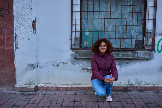 Woman crouching by urban wall outdoors