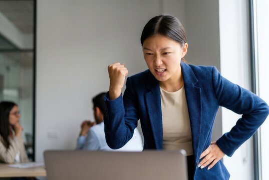 Businesswoman showing stress and anger while looking at a laptop in an office