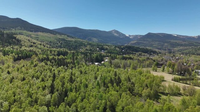 Aerial view of forest and mountain slopes with snow capped peaks of Karkonosze Mountains Poland in spring