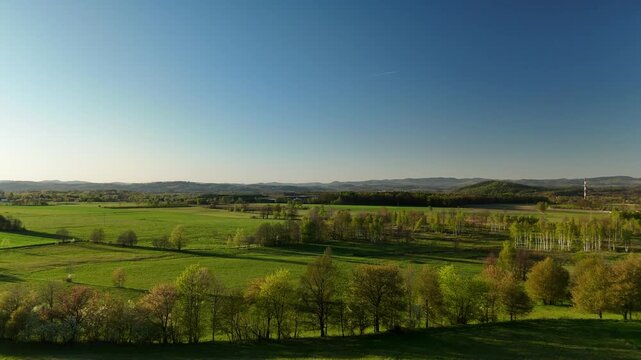 Aerial view of agricultural fields and farmland plain with distant hills at sunset in summer in Poland