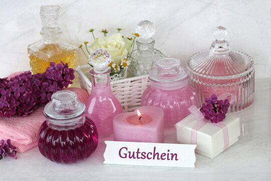 Wellness-Gutschein Stillleben mit lila Flieder, Glasflakons, Kerze und Geschenkbox.