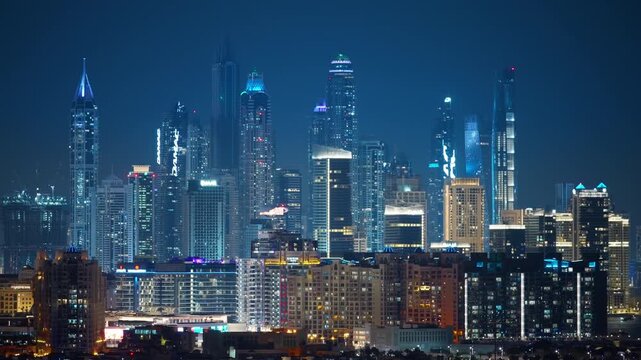 Stunning Dubai Marina skyline illuminated at night featuring dozens of glowing skyscrapers with blue and white lights against a deep navy sky, residential buildings in foreground creating urban depth.