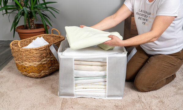 Folding clothes and organizing wardrobe with fabric storage box at home