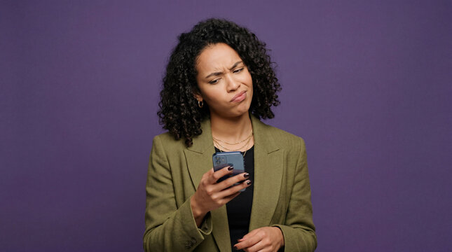 Young woman showing confused reaction while looking at mobile phone