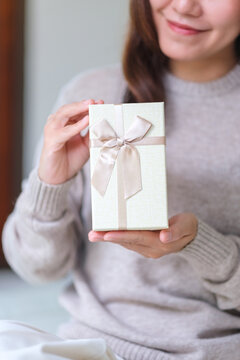 Vertical closeup image of a happy woman receiving and holding a present box at home