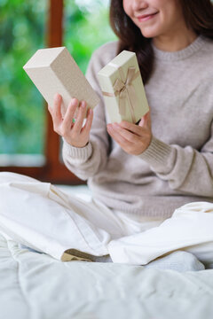 Vertical closeup image of a happy woman receiving and opening a present box at home