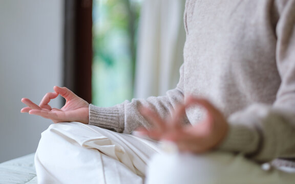 Closeup of a woman meditating or practicing yoga in lotus pose on the bed