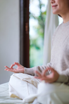 Vertical closeup of a woman meditating or practicing yoga in lotus pose on the bed