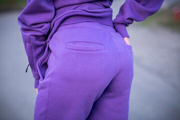 A close-up shot focusing on the back of a pair of vibrant purple sweatpants, highlighting the horizontal pocket detail and the soft fleece textile © Julia