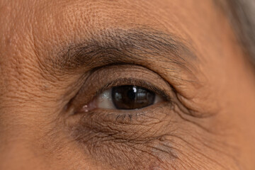 Close up macro portrait of an older senior man with dark brown eye showing deep wrinkles around...