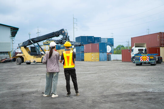 Two construction and Engineer worker under working with fork lift container truck is transportation container shipping dock yard logistics export import business concept