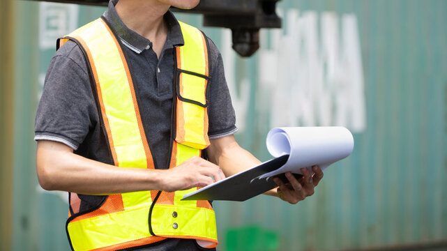 the operation or engineer construction supervisor is checking on heavy machine and equipment checklist form with crane truck as background. Industrial safety working in action