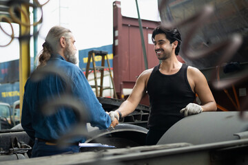 Fototapeta premium Two mechanics collaborating on truck maintenance, with a supervisor inspecting the work Handshake at an industrial vehicle depot to ensure quality control and safety