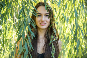 Portrait of a young beautiful woman posing in willow foliage © Andrey_Arkusha